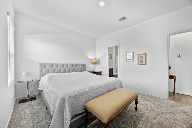 carpeted bedroom with ensuite bath and multiple windows