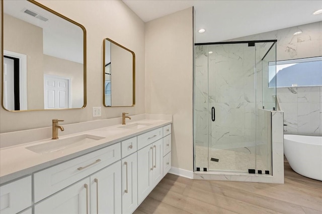 bathroom featuring a freestanding bath, wood finished floors, a sink, and visible vents