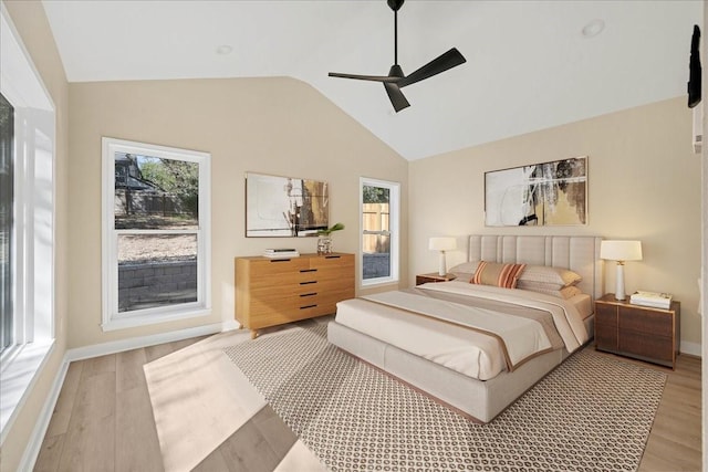 bedroom featuring light wood-type flooring, ceiling fan, baseboards, and vaulted ceiling