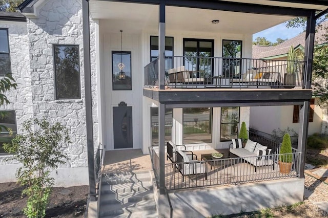 back of house featuring stone siding and a balcony