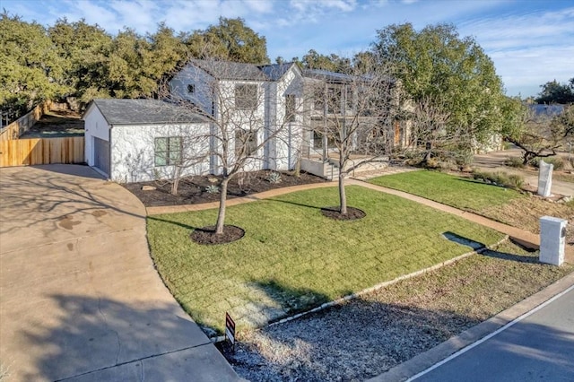 view of front of house with a front yard, driveway, an attached garage, and fence