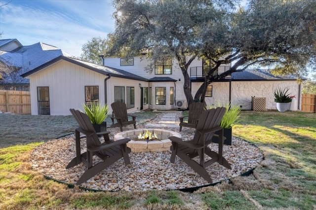 rear view of property with an outdoor fire pit, fence, and a lawn