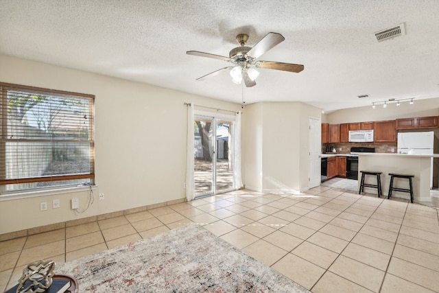 tiled spare room with ceiling fan, a healthy amount of sunlight, rail lighting, and a textured ceiling