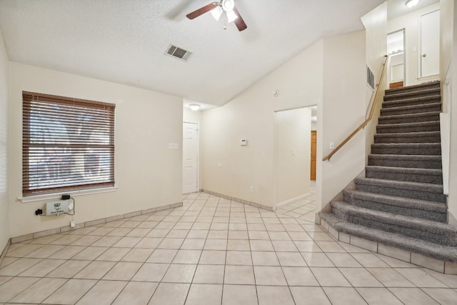 unfurnished room featuring light tile patterned flooring, a textured ceiling, vaulted ceiling, and ceiling fan