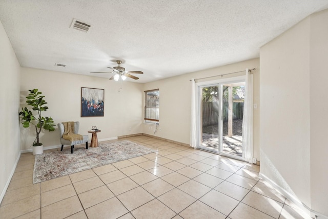 living area featuring a textured ceiling, light tile patterned floors, and ceiling fan