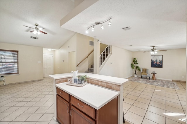 kitchen featuring ceiling fan, a center island, light tile patterned floors, and a textured ceiling