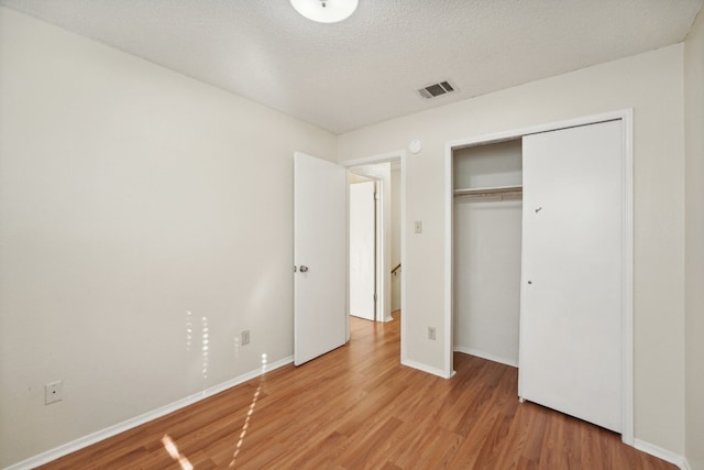 unfurnished bedroom featuring a closet, light wood-type flooring, and a textured ceiling