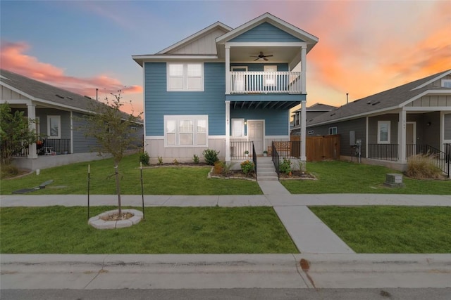 view of front of house featuring ceiling fan, a lawn, and a balcony