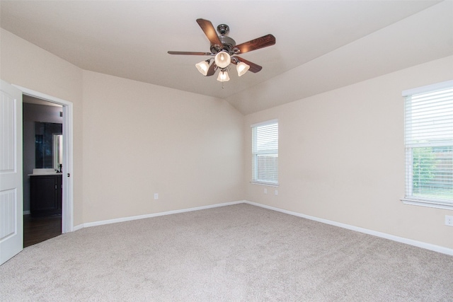 carpeted spare room with a wealth of natural light, lofted ceiling, and ceiling fan