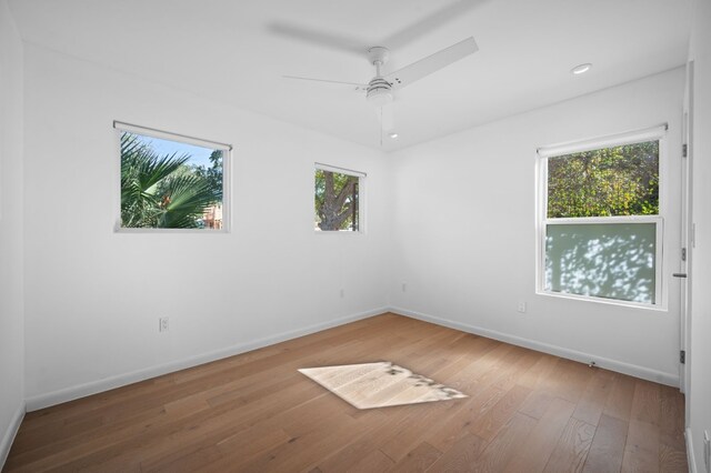 unfurnished room featuring ceiling fan, wood-type flooring, and a healthy amount of sunlight