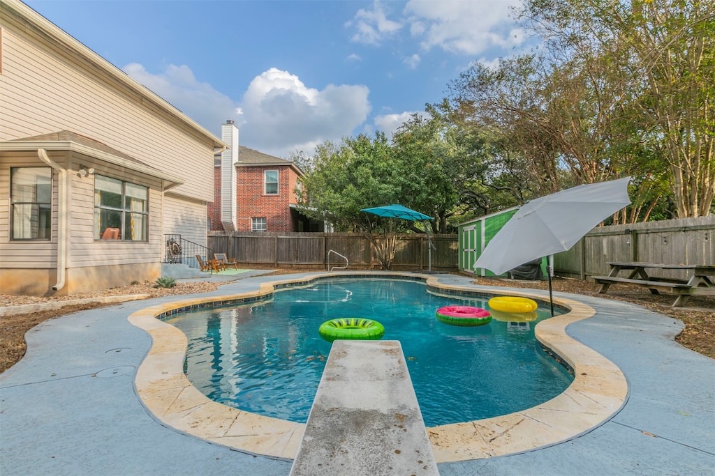 view of swimming pool featuring a diving board and a patio area