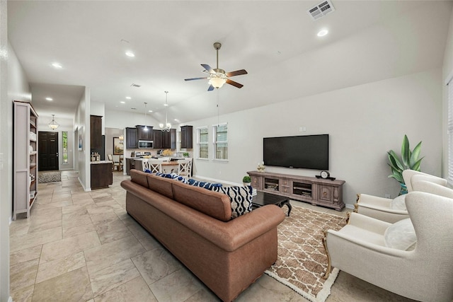 living room featuring lofted ceiling and ceiling fan with notable chandelier