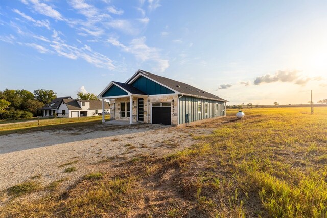 view of front of home with a garage, covered porch, and a rural view