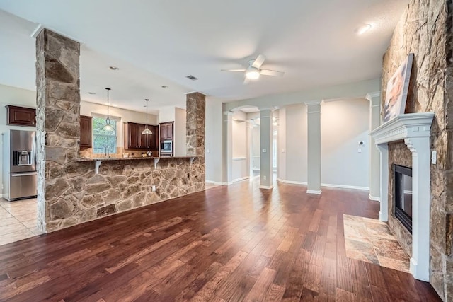 unfurnished living room with ceiling fan, light wood-type flooring, and a fireplace