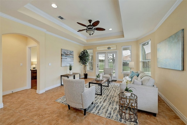 living room featuring a raised ceiling, ceiling fan, and crown molding