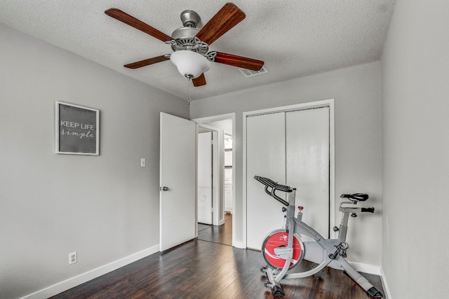 workout room with ceiling fan, a textured ceiling, and dark hardwood / wood-style floors