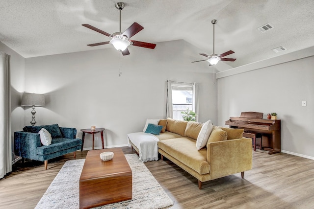 living room featuring a textured ceiling, light wood-type flooring, ceiling fan, and vaulted ceiling