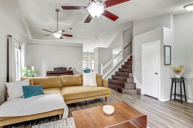 living room featuring high vaulted ceiling, hardwood / wood-style floors, ceiling fan, and a textured ceiling