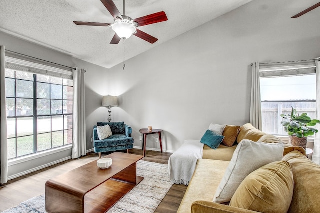 living room featuring light wood-type flooring, a textured ceiling, and ceiling fan