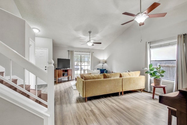 living room with lofted ceiling, ceiling fan, and light hardwood / wood-style flooring