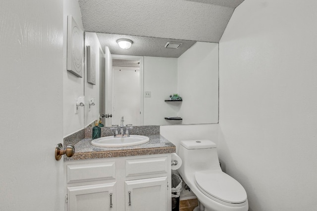 bathroom with vanity, toilet, and a textured ceiling