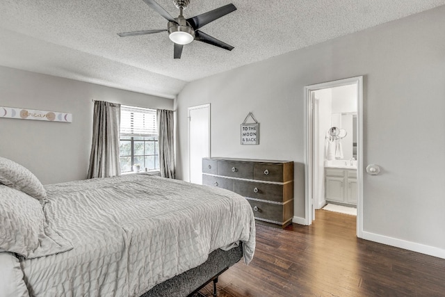 bedroom featuring ensuite bath, vaulted ceiling, a textured ceiling, dark hardwood / wood-style floors, and ceiling fan