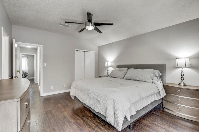 bedroom featuring dark wood-type flooring, lofted ceiling, a textured ceiling, ceiling fan, and a closet