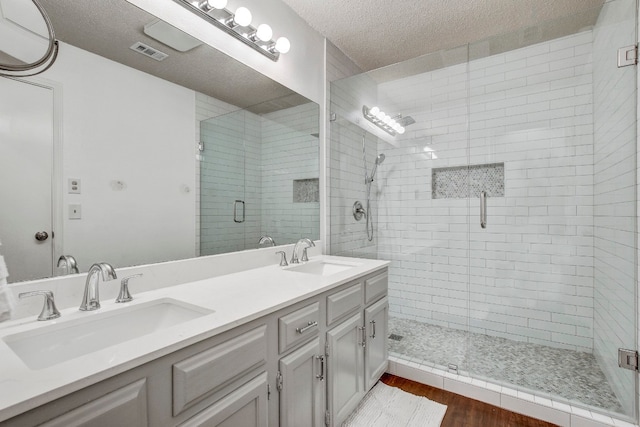 bathroom with hardwood / wood-style floors, an enclosed shower, vanity, and a textured ceiling