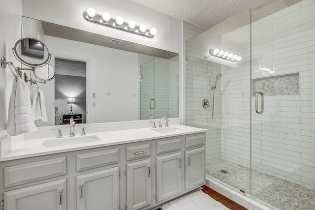 bathroom with hardwood / wood-style floors, an enclosed shower, vanity, and a textured ceiling