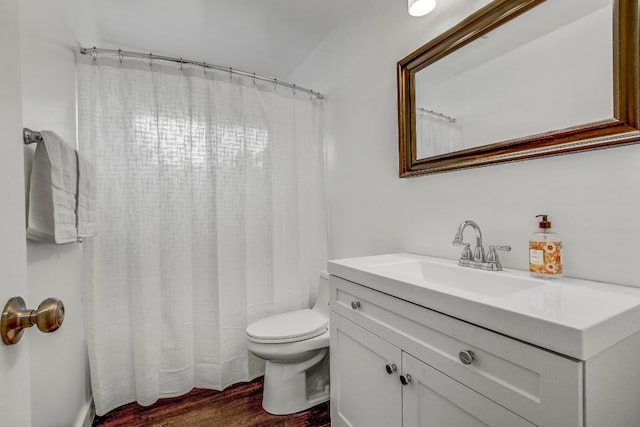 bathroom with toilet, vanity, and hardwood / wood-style floors