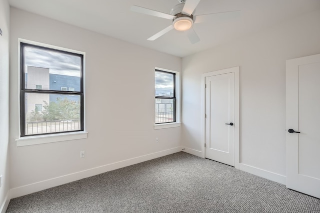 unfurnished bedroom with ceiling fan, multiple windows, and carpet flooring