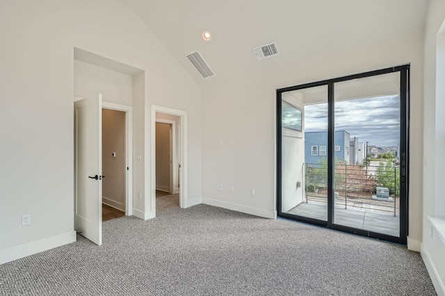 carpeted spare room with high vaulted ceiling