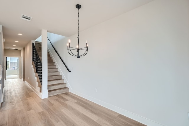 stairs featuring hardwood / wood-style floors and an inviting chandelier