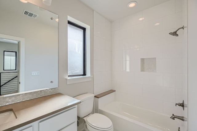 full bathroom with toilet, vanity, tiled shower / bath, and a healthy amount of sunlight