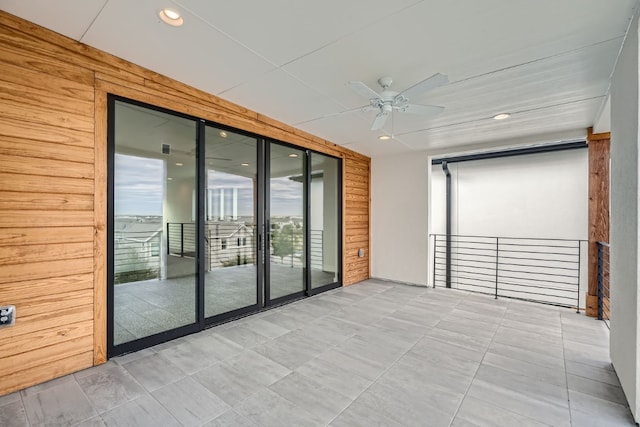 empty room featuring wooden walls and ceiling fan