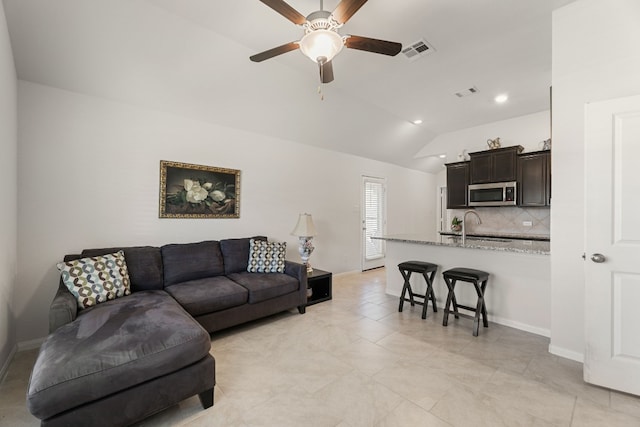 tiled living room with ceiling fan, sink, and vaulted ceiling