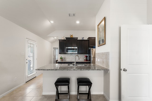 kitchen with stainless steel appliances, lofted ceiling, kitchen peninsula, sink, and tasteful backsplash