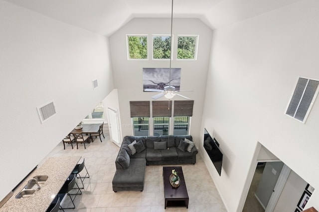 tiled living room featuring ceiling fan, sink, and high vaulted ceiling