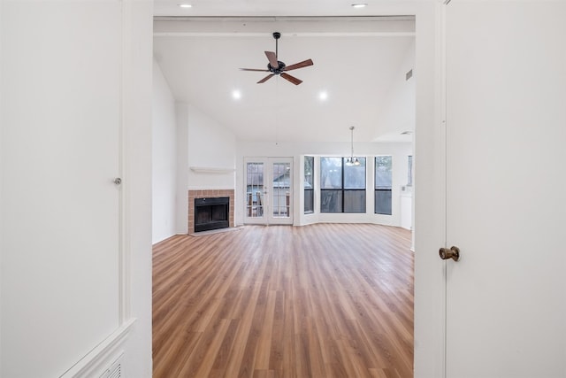 unfurnished living room with vaulted ceiling, wood-type flooring, and ceiling fan with notable chandelier