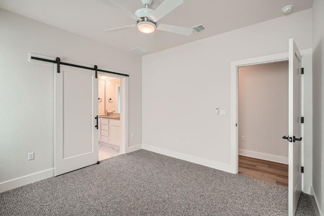 9027 Cattle Baron Path, Austin, TX 78747 - unfurnished bedroom featuring light colored carpet, a barn door, connected bathroom, and a ceiling fan