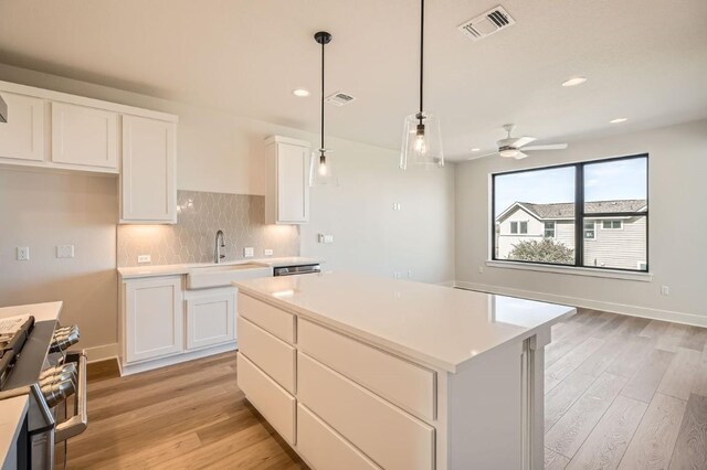 9027 Cattle Baron Path, Austin, TX 78747 - kitchen featuring stainless steel gas stove, light wood finished floors, decorative backsplash, white cabinets, and recessed lighting