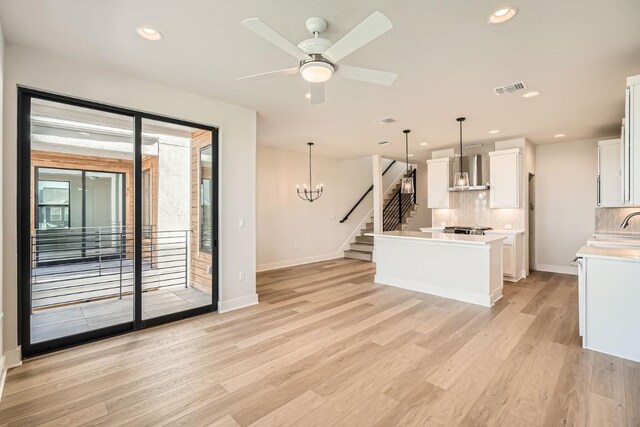 9027 Cattle Baron Path, Austin, TX 78747 - kitchen with wall chimney range hood, light wood-style floors, white cabinets, a kitchen island, and light countertops