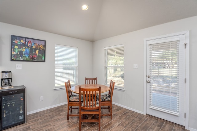 dining room featuring vaulted ceiling, dark hardwood / wood-style floors, wine cooler, and a healthy amount of sunlight