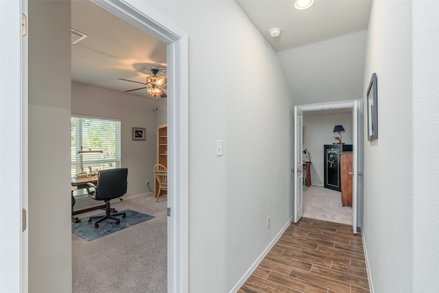 hallway with dark hardwood / wood-style floors and lofted ceiling