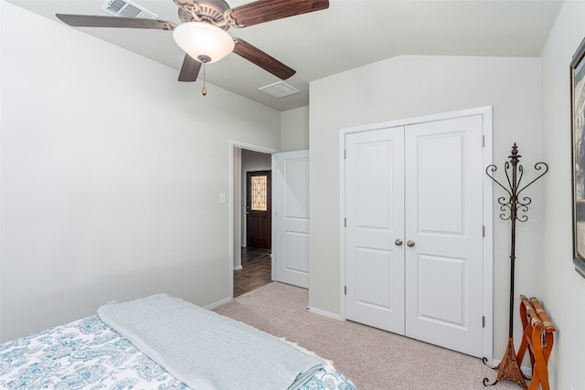 bedroom with ceiling fan, a closet, light colored carpet, and vaulted ceiling