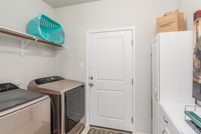 clothes washing area with cabinets and washing machine and dryer