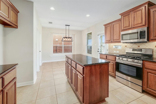 kitchen featuring stainless steel appliances, tasteful backsplash, light tile patterned floors, an inviting chandelier, and a center island