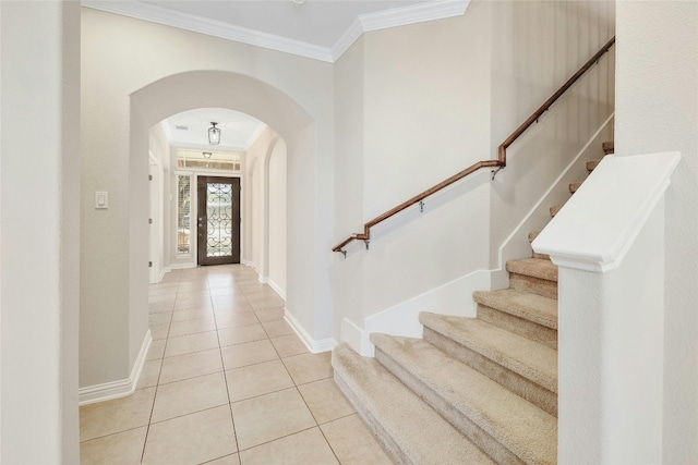 entryway with light tile patterned floors and ornamental molding