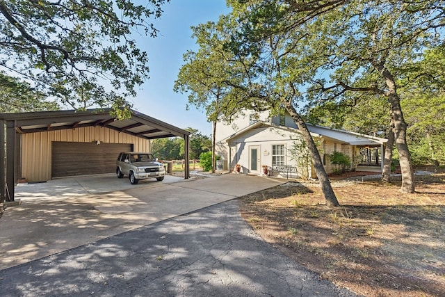 view of front of home with a garage, a carport, and an outdoor structure