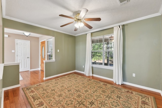 empty room featuring hardwood / wood-style flooring, ceiling fan, a textured ceiling, and ornamental molding